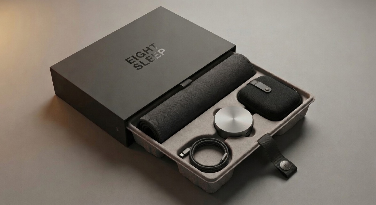 Premium unboxing: EIGHT SLEEP branded box with rolled topper pad, Pod Puck, carry case, and braided USB-C cable in molded pulp tray